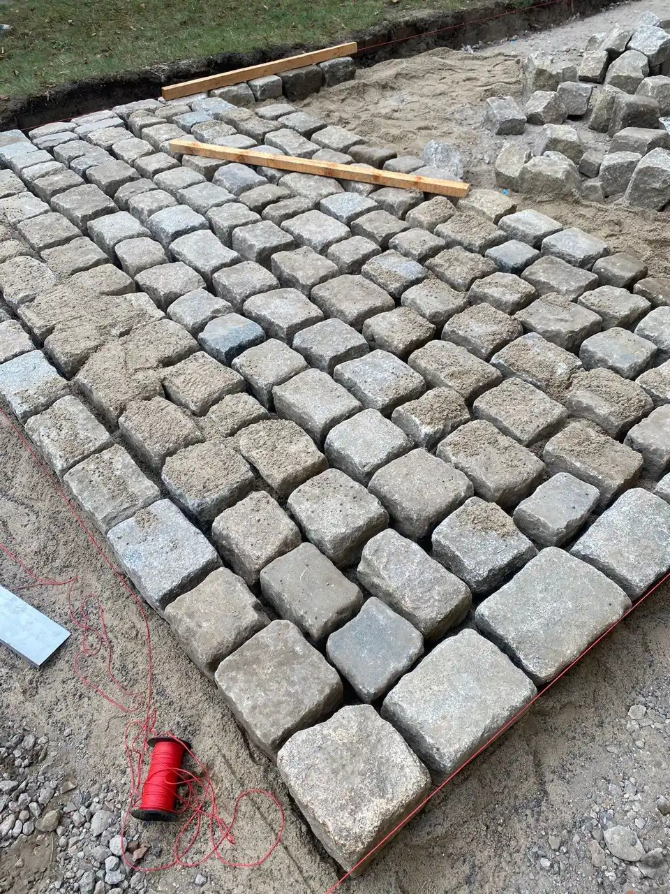 Granitkleinpflaster-Verlegung in Arbeit: Natursteine mit Ausrichtsschnur und Richtlatte – handwerkliche Präzision von Fischer Pflasterbau Berlin